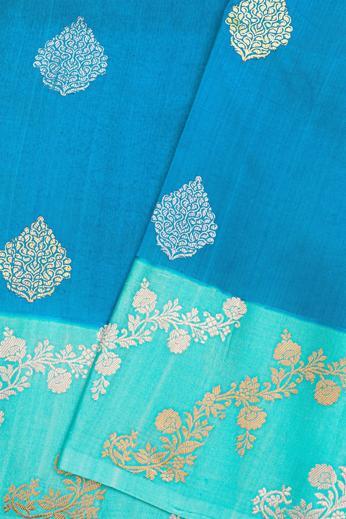 Fancy Matka Silk Peacock Blue Saree With Florals And Buttis Body And Contrast Florals And Leaves Border