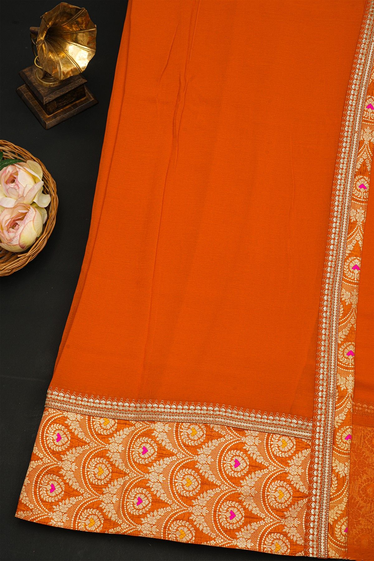 Fancy Crepe Orange Saree With All Over Plain Body And Self Design Florals And Leaves In Zari Border